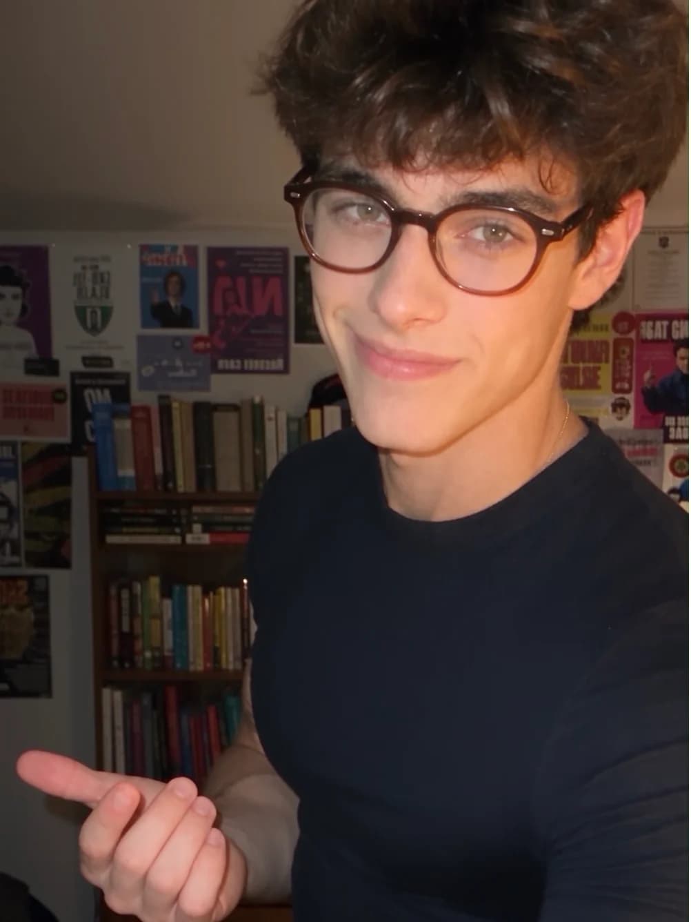 Rick wearing glasses and a dark shirt in a room with books